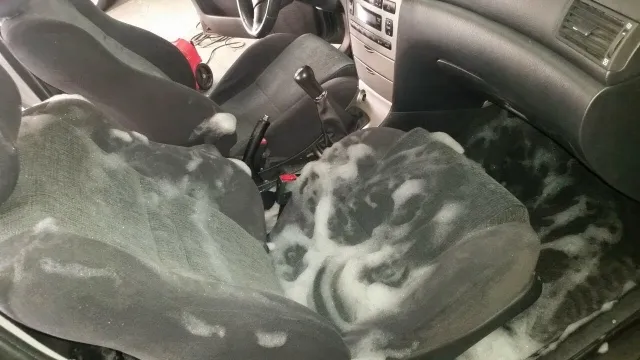 Asientos de tela de un coche cubiertos de espuma de limpieza